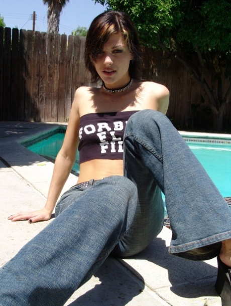 Slim alluring brunette babe with small pierced boobies posing nude by the pool